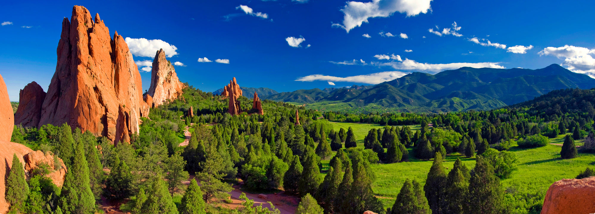 Scenic view of red rock formations and greenery with mountains in the background
