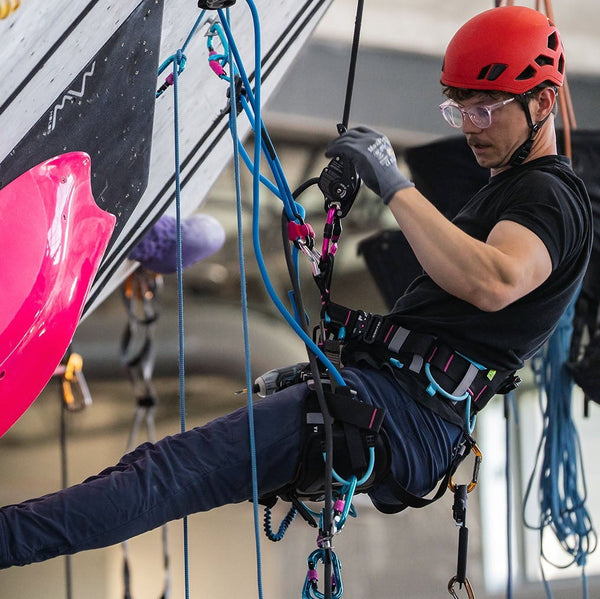 Person climbing a rock wall with colorful holds indoors